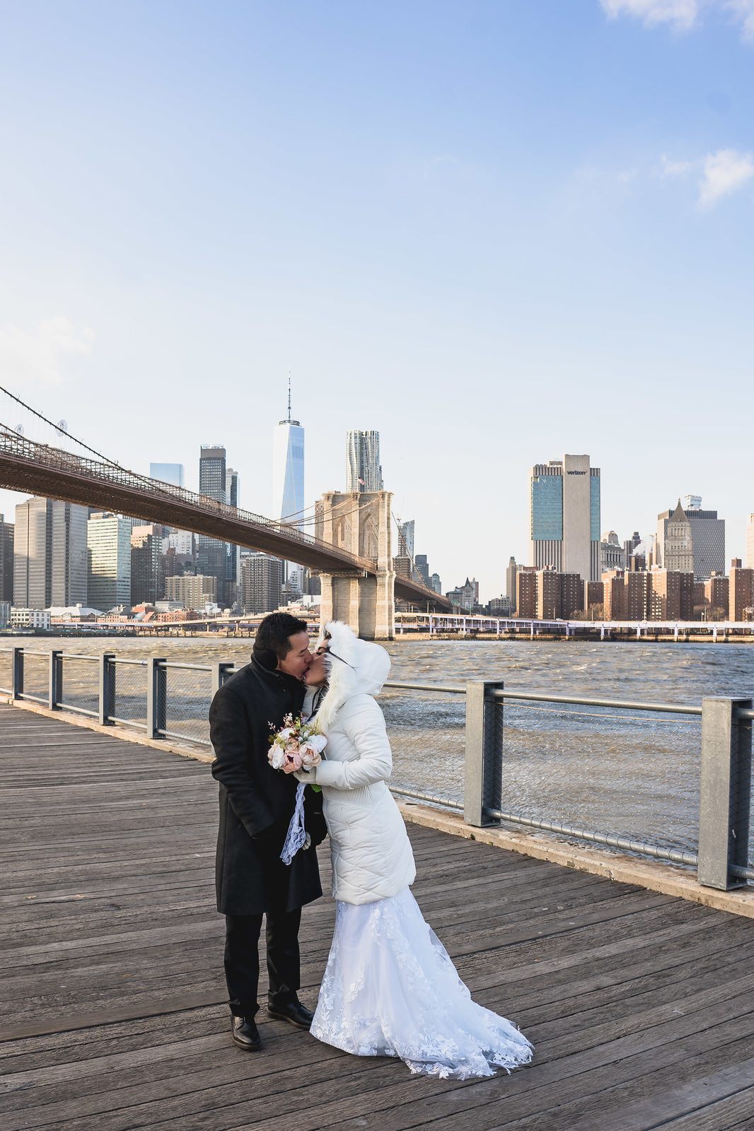 Pareja besándose con el skyline de Manhattan detrás en Brooklyn Bridge Park