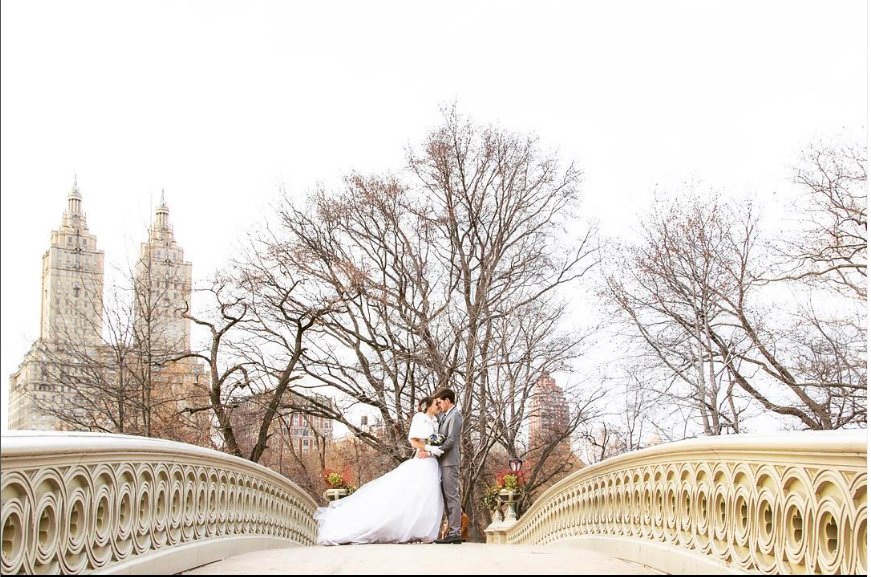 Kiss on Bow Bridge with the San Remo behind - Central Park Wedding - New York City